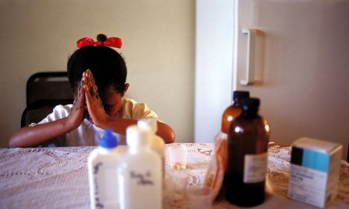 A nine-year-old girl in Johannesburg prays before taking her antiretroviral HIV-AIDS drugs.
